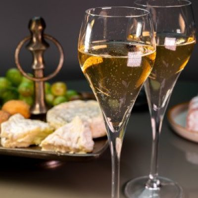 Glasses of sparkling white wine champagne or cava with bubbles and french soft cheese on background, Lyon, France